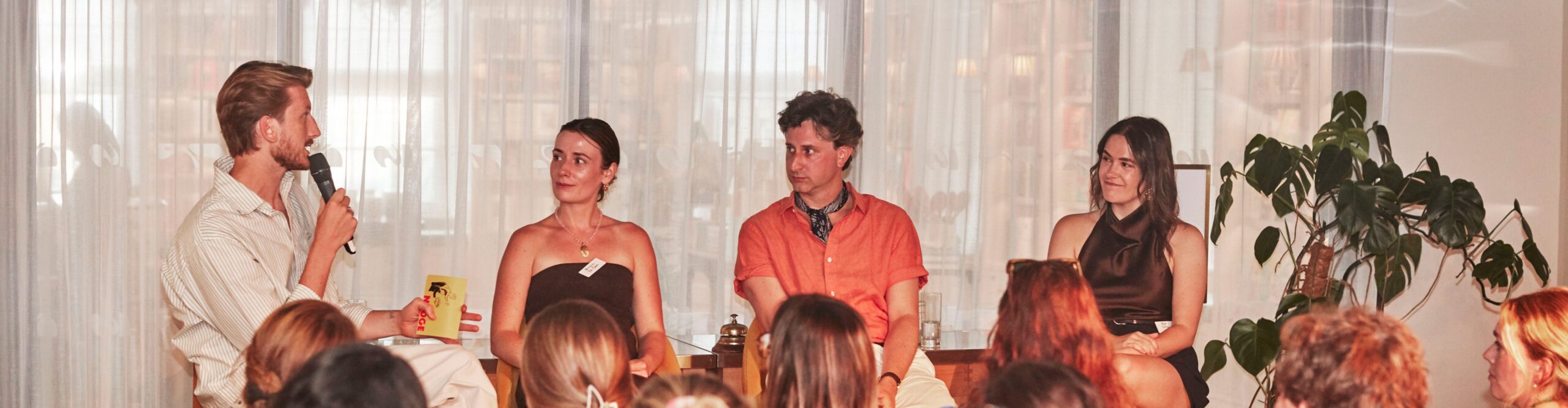 panel host speaks with journalists as audience watches on